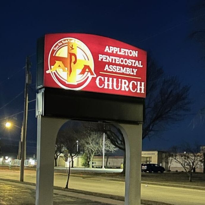 Church sign illuminated at night, street view.